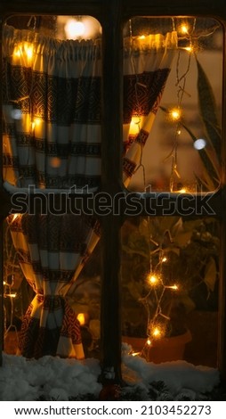 Christmas winter window. Garlands and curtains. Warm light and reflections. Snowy decorations.