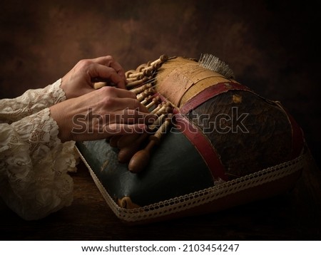 Hands of a woman working on an antique Flemish lace making pillow Royalty-Free Stock Photo #2103454247