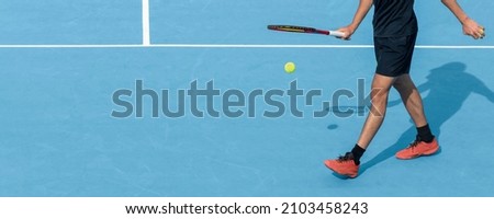 Young tennis player playing with ball and racket on blue hard tennis court during match or training. Sports active game. Tennis background, copy space Royalty-Free Stock Photo #2103458243