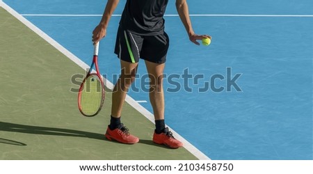 Young tennis player playing tennis on blue hard court. Male athlete with ball and racket is ready to serve at start of game. Sports background, copy space Royalty-Free Stock Photo #2103458750