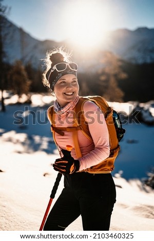 Mountaineer backcountry ski walking ski alpinist in the mountains. Ski touring in alpine landscape with snowy trees. Adventure winter sport. Royalty-Free Stock Photo #2103460325