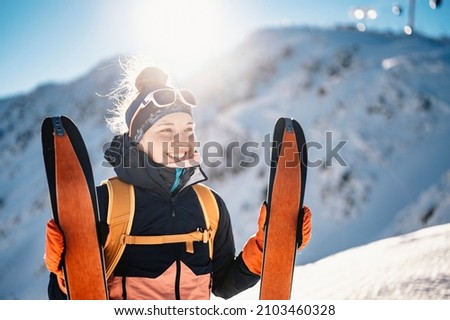 Mountaineer backcountry ski walking ski alpinist in the mountains. Ski touring in alpine landscape with snowy trees. Adventure winter sport. Royalty-Free Stock Photo #2103460328