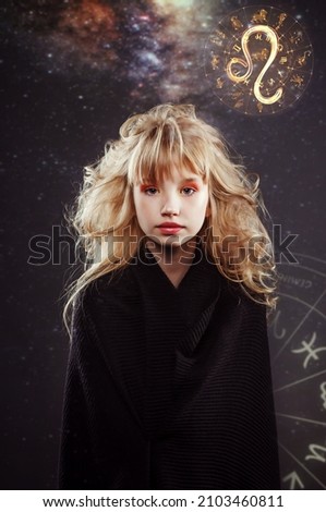 Blond hair beautiful little girl in wearing in white t-shirt and black mantle show horoscope symbols zodiac signs hold fire and water with astrological background