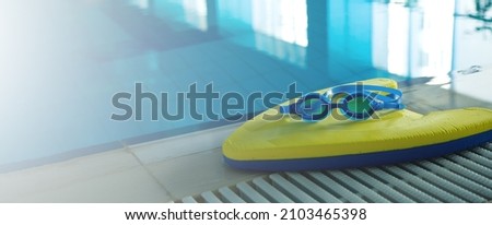 Swim board with Goggles on beside of the swimming pool in sports center. swimming training concept. banner copy space for text Royalty-Free Stock Photo #2103465398