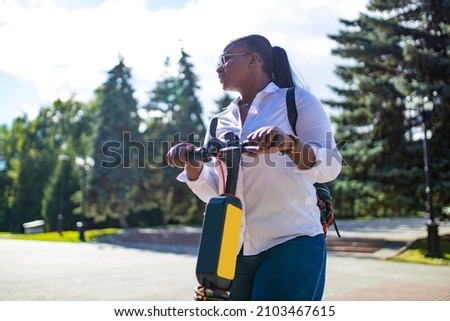 multiracial race woman riding an electric scooter in the summer on the street