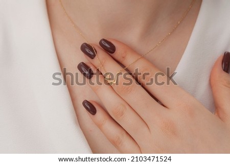 Attractive female model with initials silver necklace around her neck. Jewelry photo for e commerce, online sale, social media.