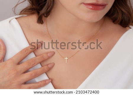 Attractive female model cross silver necklace. Woman wearing religious jewellery. Jewelry photo for e commerce, online sale, social media. Royalty-Free Stock Photo #2103472400