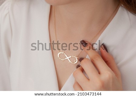 Name silver necklace on attractive female model. Woman wearing personalized necklace. Jewelry photo for e commerce, online sale, social media. Royalty-Free Stock Photo #2103473144