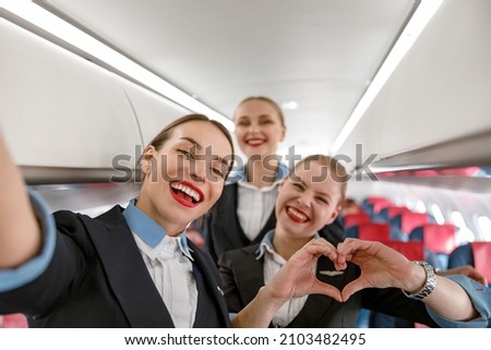 Cheerful flight attendants having fun in airplane Royalty-Free Stock Photo #2103482495