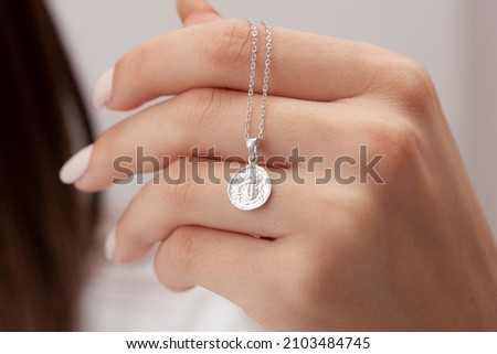 The silver necklace is in the foreground on the woman's nail polished hands. Jewelry images that can be used in e-commerce, online sales and social media. Royalty-Free Stock Photo #2103484745