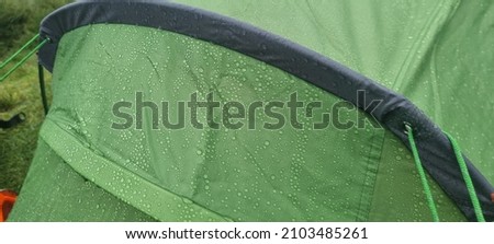 Rainwater droplets on Bright green waterproof tent Royalty-Free Stock Photo #2103485261