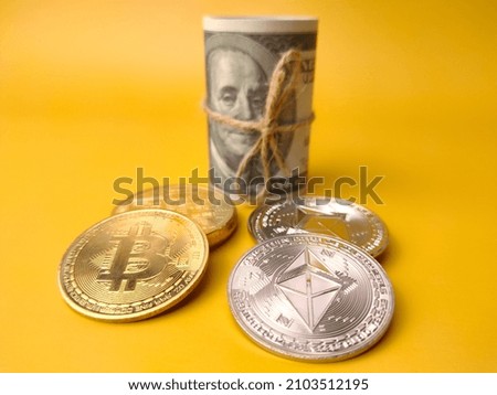 Banknotes with silver ethereum and golden bitcoin digital crypto coin on yellow background