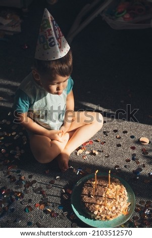 Top view of a caucasian boy sitting on floor and blowing birthday candles out. Holiday, birthday. Sweet food. Birthday party.