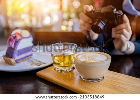 Woman using digital camera for take photo of cake and coffee in the cafe. Relax and recreation alone on holiday.