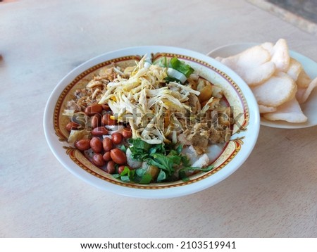 Bubur ayam or chicken porridge, Indonesian rice with additional toppings of shredded chicken and fried peanuts and crackers, Royalty-Free Stock Photo #2103519941