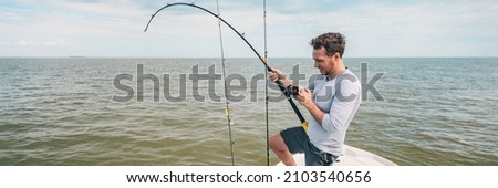 Fishing young man with sport fish rod and reel line for recreation on summer ocean day. Recreational fishing fisherman outdoor leisure lifestyle. Royalty-Free Stock Photo #2103540656