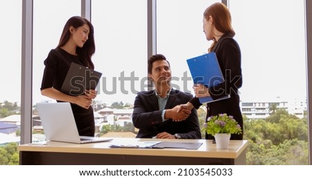 Business people shaking hands and smiling their agreement to sign contract and finishing up a meeting 