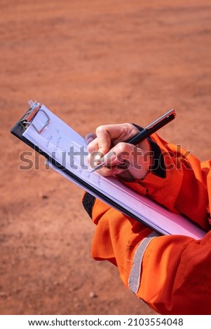 A supervisor is taking note on paper during perform inspection audit and safety group meeting. People working in the industrial action scene photo. Close-up and selective focus at hand's part.