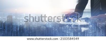 Business finance and investment concept. Double exposure of businessman working on laptop computer and the city, office buildings for business and financial technology background, panorama web banner