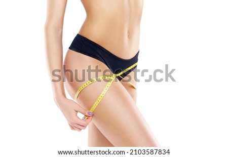 Young and fit female body close-up. Waist of beautiful and slender woman with measuring tape isolated on white. Sport, fitness, diet and healthy eating concepts.