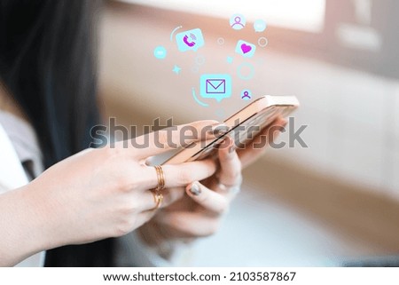 Hands of a woman holding a smartphone with social media notification symbols. Social media and digital online concept