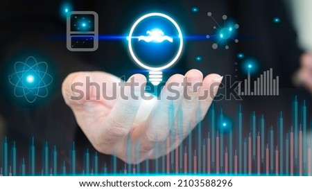A businessman holds a virtual energy-saving concept lamp, a digital hologram. Virtual reality growth, future technology, constraints, mutual funds, stock markets and digital assets Royalty-Free Stock Photo #2103588296