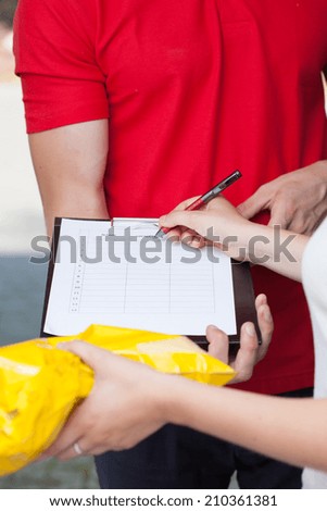 Close-up of a woman signing document of delivered package