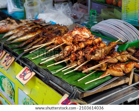 Roast chicken or Kai yang or ping gai is street food from the Lao people of Laos and Isan, but it is now commonly eaten throughout the whole of Thailand. street food style Royalty-Free Stock Photo #2103614036
