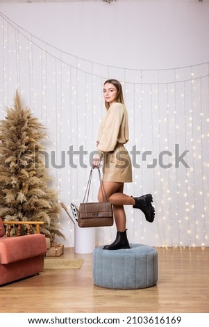 Beautiful pretty woman with long hair in a beige leather skirt and a sweater stands in new leather shoes