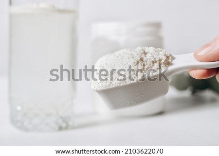 hand holding scoop of fish collagen. collagen peptides in container or jar. powder for mixing drink. Healthcare supplement concept. collagen for skin and joints Royalty-Free Stock Photo #2103622070