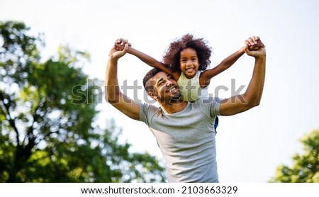 Portrait of happy black father carrying daughter on back outdoors. Family happiness love concept. Royalty-Free Stock Photo #2103663329
