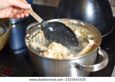 cooking soup in a saucepan on the stove in the kitchen. skim the broth