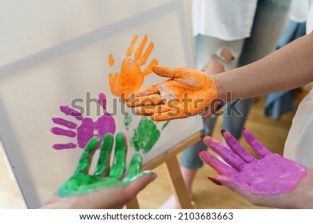 Closeup of female palms in colorful paint creating modern artwork
