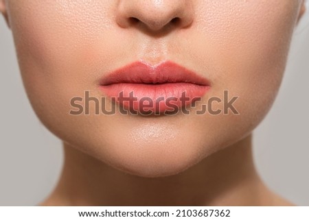Closeup of female lips after permanent makeup lip blushing procedure Royalty-Free Stock Photo #2103687362