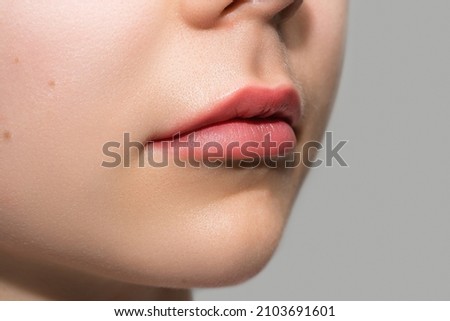 Closeup of female lips after permanent makeup lip blushing procedure Royalty-Free Stock Photo #2103691601