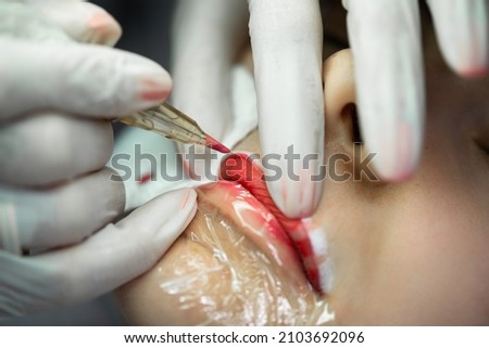 Young woman during professional permanent makeup procedure - lip blushing Royalty-Free Stock Photo #2103692096