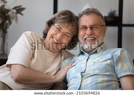Portrait of happy bonding middle aged senior retired married couple relaxing on comfortable sofa, enjoying lovely sweet tender relaxed weekend pastime together at home, good family relations concept.