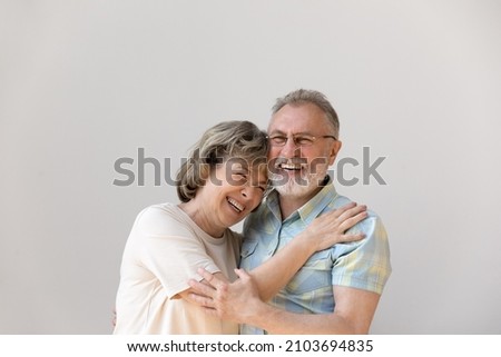 Sincere laughing bonding happy middle aged senior married couple cuddling, having fun enjoying communicating, isolated on white wall, showing candid loving feelings, good family relations concept. Royalty-Free Stock Photo #2103694835