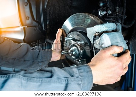 Checking the brake discs of a modern car. Vehicle braking system. Royalty-Free Stock Photo #2103697196