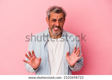Middle age caucasian man isolated on pink background  rejecting someone showing a gesture of disgust.