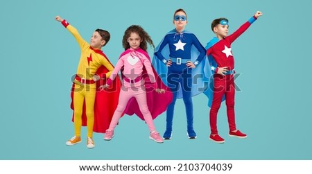 Group of brave superhero children in bright costumes standing together on blue background in studio Royalty-Free Stock Photo #2103704039