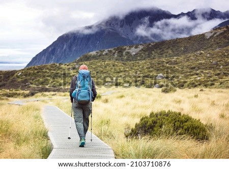 Man walking on hike trail route with Mount Cook National Park, beautiful mountains region. Tramping, hiking, travel in New Zealand. Royalty-Free Stock Photo #2103710876