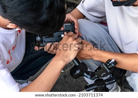 a young man photographers working as a team to setting up the camera and gimbal for their job on the sidewalk