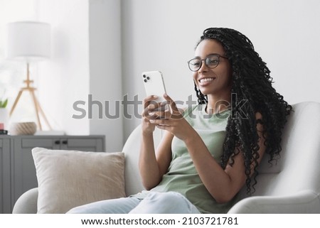 Woman using smartphone at home. Mixed race girl looking at mobile phone. Communication, leisure, connection, mobile apps, technology, learning, web chat, lifestyle concept Royalty-Free Stock Photo #2103721781