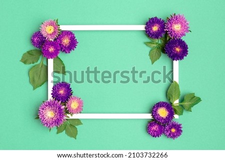 Happy Mother's Day, Women's Day, Valentine's Day or Birthday Pastel Green Background. Green colored flat lay greeting card template with beautiful purple flowers and empty picture frame.