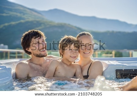Portrait of young carefree happy smiling happy family relaxing at hot tub during enjoying happy traveling moment vacation. Life against the background of green big mountains Royalty-Free Stock Photo #2103748205