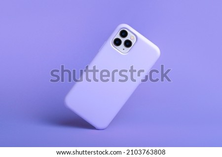 iPhone 11 and 12 Pro max in purple silicone case falls down back view, phone case mockup isolated on purple background view very peri 2022 color Royalty-Free Stock Photo #2103763808