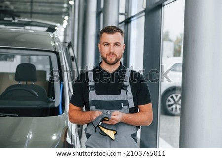 Tools in hands. Man in uniform is working in the autosalon at daytime. Royalty-Free Stock Photo #2103765011