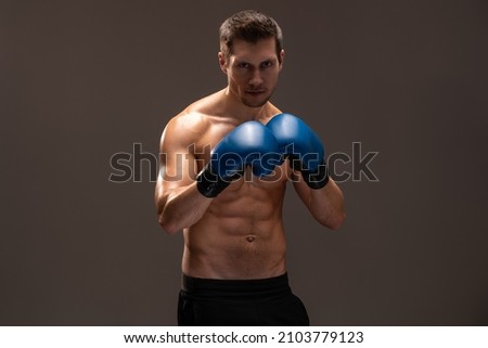 Waist up portrait view of the sportsman boxer fighting in gloves in boxing cage isolated on brown background. Stock photo 