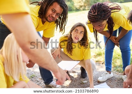 Young people in the startup team discuss direction in a geocaching game in nature Royalty-Free Stock Photo #2103786890